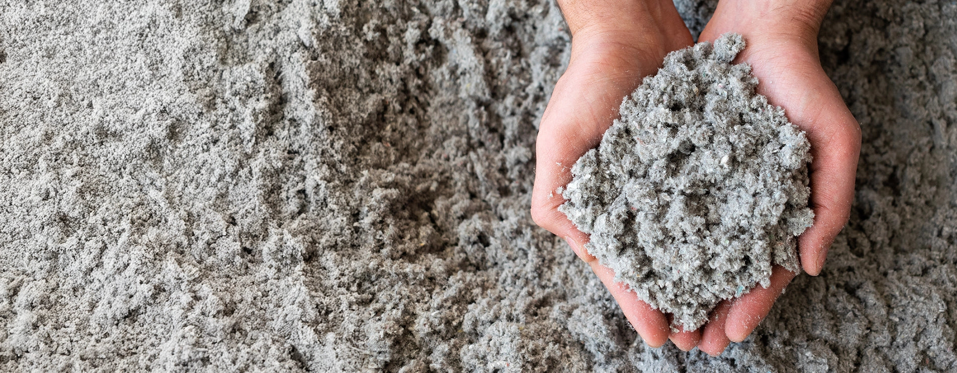 Close-up van cellulose-isolatievlokken in handen — ecologisch isolatiemateriaal gemaakt van gerecycleerd papier voor duurzame toepassingen.