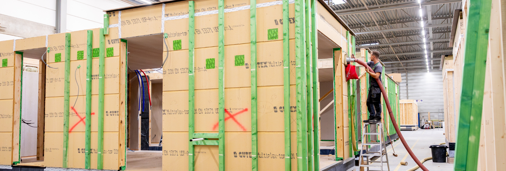 Inblazen van cellulose-isolatie in prefab houtskeletwanden voor luchtdichte en energie-efficiënte houtconstructie.