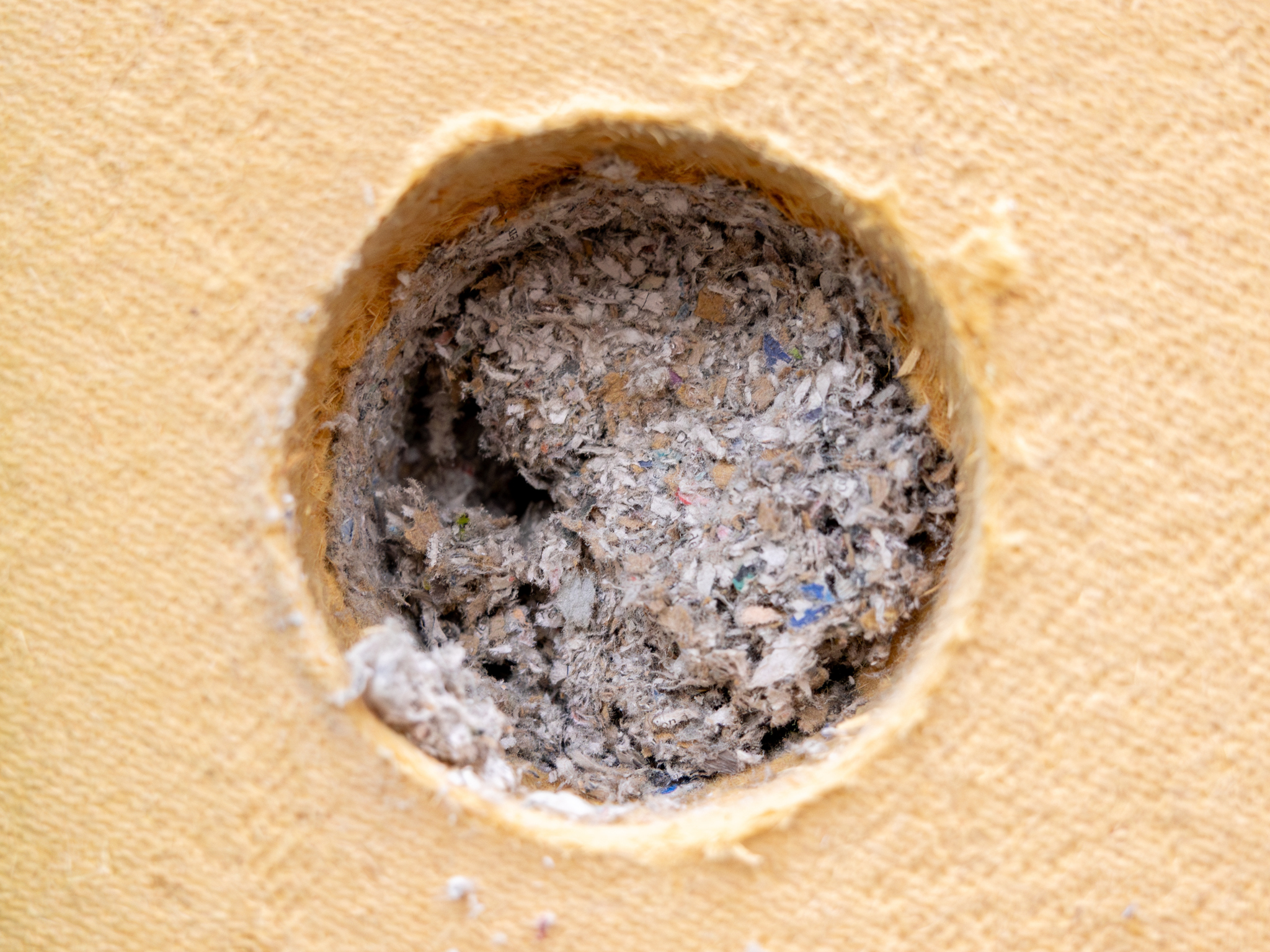 Close-up van cellulose-isolatie ingeblazen in een houtskeletwand.