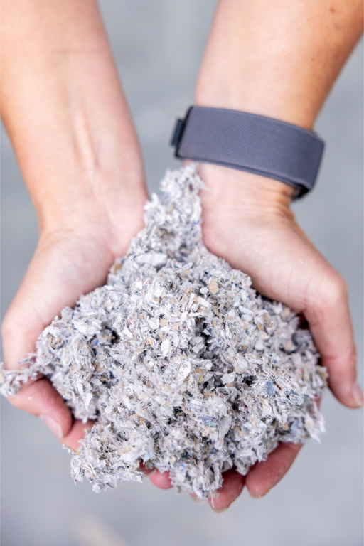 Close-up van cellulose-isolatievlokken in handen — ecologisch isolatiemateriaal gemaakt van gerecycleerd papier voor duurzame toepassingen.